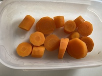 Des carottes cuites en rondelles dans une boîte en plastique