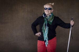Je pose, cheveux court et mini couette, foulard bleu-vert, pull noir, pantalon rouge. J'ai gardé mes solaires. Je tiens à bout de bras ma canne de signalement, verticale, comme s'l s'agissait d'un sceptre.